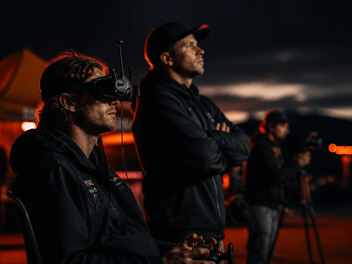 FPV pilot in goggles flying with a spotter beside him